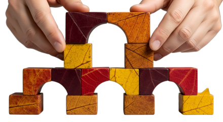 Building autumn-themed wooden blocks into an arch structure, two hands demonstrating collaboration and creativity, ideal for education, team building, fall promotions, or Thanksgiving concepts,