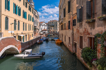 Venetian Canal Scene: Boats bob on the water, framed by colorful buildings and charming bridges, capturing the city's unique beauty.