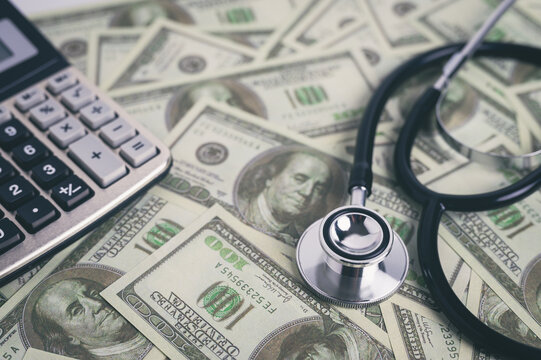 Close-up of stethoscope and calculator on dollar bills symbolizing healthcare costs and medical insurance, financial impact of medical treatment