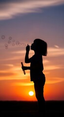 A silhouette of a young child blowing bubbles against a vibrant sunset, capturing a moment of pure childhood joy and wonder in a siluet