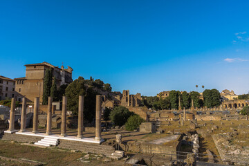 Roman Forum Ruins: Ancient columns and archaeological remains stand under a clear blue sky,...