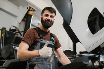 Mechanic showing thumbs up while repairing truck in garage