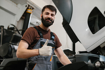 Mechanic showing thumbs up after repairing truck in garage