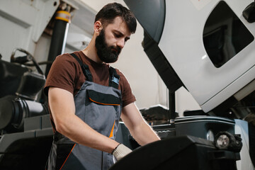 Mechanic repairing truck engine in garage workshop