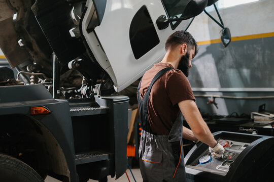 Auto mechanic repairing truck air conditioning system in garage - Powered by Adobe
