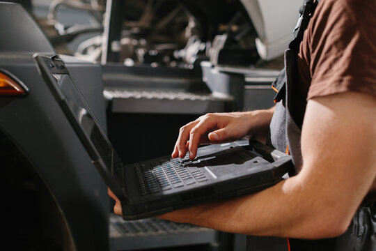 Professional auto mechanic using laptop for truck diagnostics in repair shop