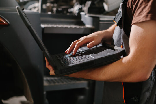 Professional auto mechanic using laptop for truck diagnostics in garage