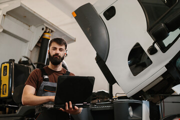 Mechanic using laptop for truck diagnostics in repair shop