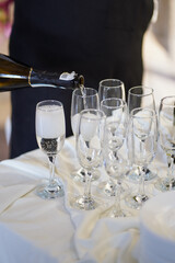 White champagne is poured into glasses on a tray.
