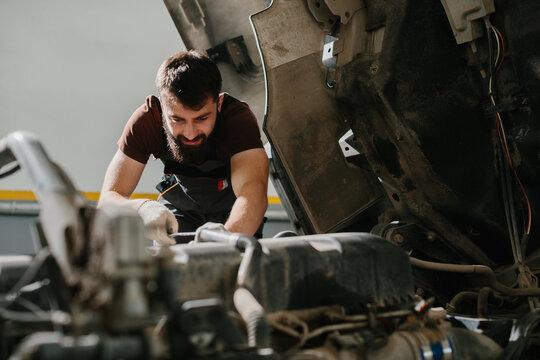 Professional auto mechanic repairing truck engine in garage