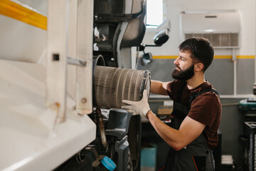 Mechanic replacing air filter of truck in garage