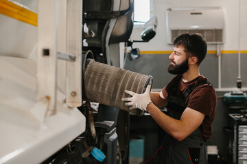 Mechanic replacing air filter in a truck engine
