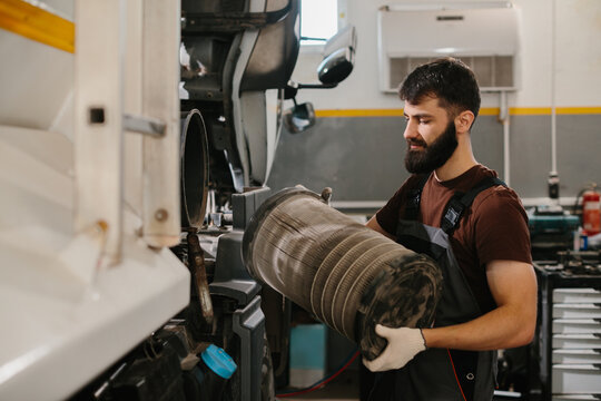 Auto mechanic replacing dirty air filter in truck at repair shop