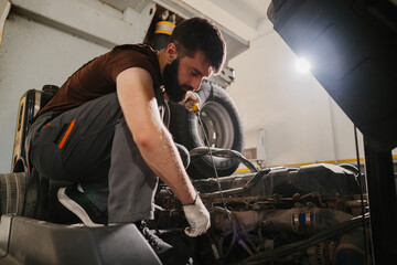 Mechanic checking oil level in truck engine during maintenance