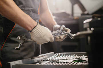Auto mechanic choosing right wrench for repairing trucks in workshop