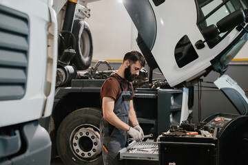 Professional auto mechanic choosing right wrench for repairing truck in garage © dsheremeta