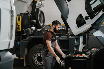 Mechanic repairing truck engine in garage workshop