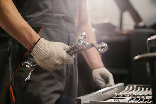 Auto mechanic holding wrenches, preparing for truck repair in garage