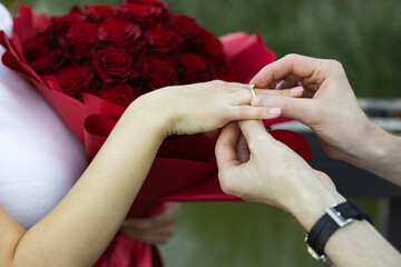 Romantic engagement proposal by the lake with roses and a gold ring during sunset