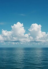 Fototapeta premium Serene ocean view featuring cumulus clouds under a clear blue sky