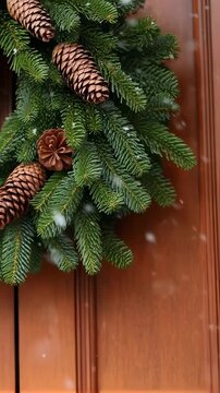 A Beautiful Winter Wreath Adorned with Pinecones and Fresh Evergreen Decorates a Warm Wooden Door, Bringing Cheer to the Season