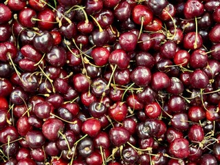 Red ripe cherries, which are used in abundance to make delicious seasonal delicacies and flavors. Bright cherries are beautifully stacked on top of each other, showing off their delicious juiciness