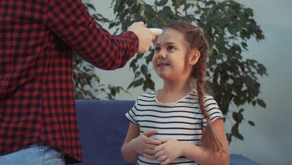 mom measures the temperature with an infrared thermometer, the little girl fell ill coronavirus. covid 19 lockdown stay home social distance coronavirus. temperature measurement during coronavirus