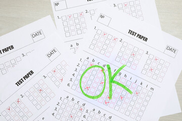 Answer sheets with word Ok on wooden table, top view. Student passing exam
