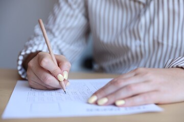 Student filling out multiple choice test at table in class, closeup. Passing exam