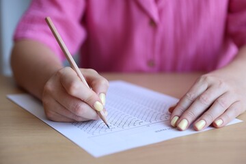 Student filling out multiple choice test at wooden table, closeup. Passing exam