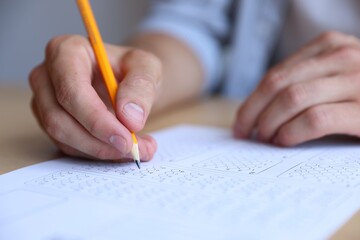 Student filling out multiple choice test at table in class, closeup. Passing exam