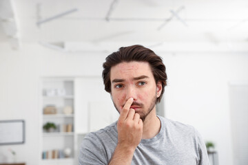 Young man with acne problem at home. Space for text
