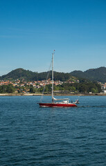 A sailboat in the estuaries of Galicia sails through the estuary to reach the sea.