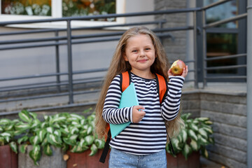 Cute little girl eating apple outdoors. School lunch
