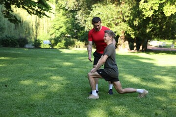 Obraz premium Young man exercising with professional personal trainer outdoors. Space for text