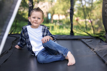 Cute little boy posing on black trampoline outdoors