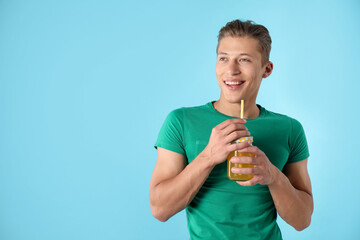 Man with juice and drinking straw on light blue background, space for text