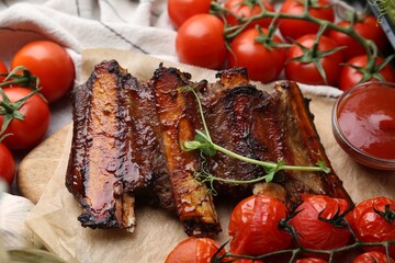 Roasted beef ribs with microgreens, tomatoes and sauce on table, closeup