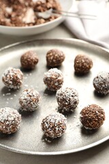Tasty chocolate candies with nuts and coconut flakes on light table, closeup