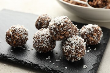 Tasty chocolate candies with nuts and coconut flakes on light table, closeup