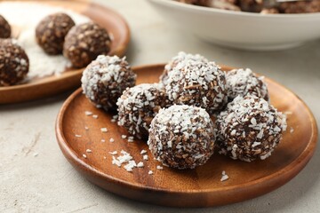 Tasty chocolate candies with nuts and coconut flakes on light table, closeup