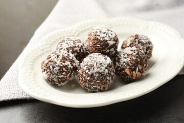 Tasty chocolate candies with nuts and coconut flakes on grey table, closeup