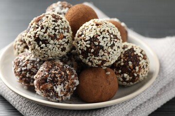 Tasty chocolate candies with cocoa powder, nuts and sesame seeds on table, closeup