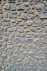 Close-Up Gray Stone Wall Texture with Natural Rough Surface, Weathered Interlocking Stones and Neutral Gray-Beige Pattern Background