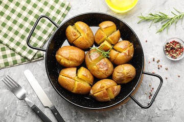 Tasty baked potatoes with rosemary served on light grey table, flat lay