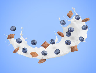Splashing milk with sweet corn pads and fresh blueberries in air against light blue background. Healthy breakfast