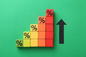 Colorful cubes with percent signs and arrow on green background, top view