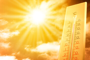 Extremely high temperature on thermometer against orange sky on sunny day. Severely hot summer weather