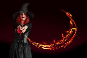 Witch with a magic wand casts a spell. Young woman, magician girl with red hair, dressed in...