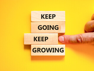 Keep going and growing symbol. Concept words phrase Keep going keep growing on beautiful wooden blocks. Beautiful yellow background. Businessman's hand. Business Keep going growing concept. Copy space